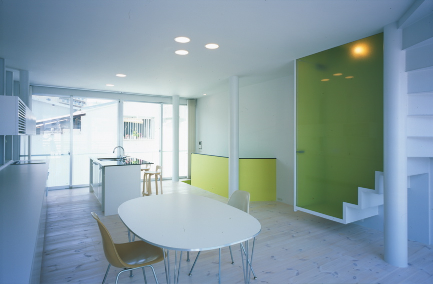 Mo House この住宅は、商店街と住居地が混在する比較的密集した18坪足らずの狭小地に建つ、コンパクトなスチールシートの都市型住宅である。1階には、住宅に付属する店舗と視覚的に連続する中庭があり、上階にそのクライアントの住まいがある。神戸の地形から、海と山を結ぶ南北軸に両方向をペアガラスのサッシュで全面開放させ、敷地奥に中庭を確保したことでパッシブにとらえた自然採光と風抜きが十分に機能できている。そして、2階に個室、3階にリビングをそれぞれ配し、下階から上階に上がるにつけ内部ヴォリュームが増し、さらに開放感と光量が増大するように考えている。サニタリーのある屋上テラスは、デッキと緑のある空中庭園としてアウトリビングとなり、都市にいながらにして天空と山と海側の風景が楽しめる場所である。<br />スチールがもつ魅力は、モダニズムの時代に確立された構造的規制を超える可能性がある材料であると思えるからで、まだその応用と展開が可能と私自身は確信している。そして構造材としてのスチールシート材のもつ性能もさることながら、建築のクオリティの選択としてスチールシートを外装材として考えている。<br />9mmのスチールシートの使用は、スチール自体の素材感の強さや強度よりも、厚さが語りかける質感を期待するからである。その質感は、ミースが使う石材の厚さと同様に、安心感と建築のクオリティを保証してると確信するからである。車は車であり軽くて強度が必要で、車体を包む薄肉のスチールシートで、決して建築のように質感は問われないはずである。建築のスチールシート化は、単なるプロダクト的な工場制作の工法における扱いだけでもなかろう。素材の厚さは、やはり空間の大きさに比例し、質感に反映すると思える。質感が求められるのは、使われるもの以上に人が住まうものであるという決定的な点にある。