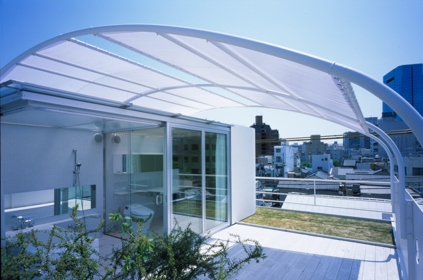 Mo House この住宅は、商店街と住居地が混在する比較的密集した18坪足らずの狭小地に建つ、コンパクトなスチールシートの都市型住宅である。1階には、住宅に付属する店舗と視覚的に連続する中庭があり、上階にそのクライアントの住まいがある。神戸の地形から、海と山を結ぶ南北軸に両方向をペアガラスのサッシュで全面開放させ、敷地奥に中庭を確保したことでパッシブにとらえた自然採光と風抜きが十分に機能できている。そして、2階に個室、3階にリビングをそれぞれ配し、下階から上階に上がるにつけ内部ヴォリュームが増し、さらに開放感と光量が増大するように考えている。サニタリーのある屋上テラスは、デッキと緑のある空中庭園としてアウトリビングとなり、都市にいながらにして天空と山と海側の風景が楽しめる場所である。<br />スチールがもつ魅力は、モダニズムの時代に確立された構造的規制を超える可能性がある材料であると思えるからで、まだその応用と展開が可能と私自身は確信している。そして構造材としてのスチールシート材のもつ性能もさることながら、建築のクオリティの選択としてスチールシートを外装材として考えている。<br />9mmのスチールシートの使用は、スチール自体の素材感の強さや強度よりも、厚さが語りかける質感を期待するからである。その質感は、ミースが使う石材の厚さと同様に、安心感と建築のクオリティを保証してると確信するからである。車は車であり軽くて強度が必要で、車体を包む薄肉のスチールシートで、決して建築のように質感は問われないはずである。建築のスチールシート化は、単なるプロダクト的な工場制作の工法における扱いだけでもなかろう。素材の厚さは、やはり空間の大きさに比例し、質感に反映すると思える。質感が求められるのは、使われるもの以上に人が住まうものであるという決定的な点にある。