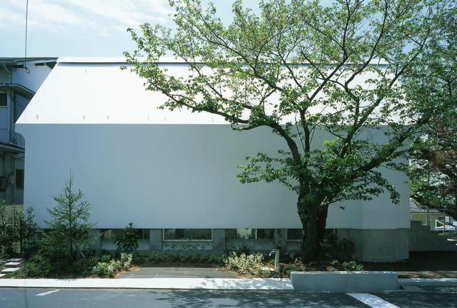 鉄の教会/神戸新生バプテスト教会 私自身、旅の傍ら教会をおつずれることが多い。街の象徴として、歴史、人々の営みの結晶なるものとして、無言ながら語りかけて来る。そして、無機質な石の素朴さや冷ややかな沈黙のその緊張感に触れた時、神聖さと生命の尊厳を感じる。神戸新生バプテスト教会は、元々、牧師住宅に併設された小さな礼拝所であった。しかし、アメリカに本部を置く団体の撤退方針に伴い売却され、残された信者達によって、牧師が居ないまま自立再建を余儀なくされた。そして、支援者達と学生ボランティアを含めワークショップ方式によるもので、実現に向けての資金調達、形が見えない計画段階から実際の具現化に至る、その方法論を導き出して行くプロジェクトでもあった。<br /> この鉄の教会は、礼拝堂とその下階に事務と集会機能を併設させた施設である。厳しいコスト制約の為、ほぼ直営に近い方式で建設は進められた。そして、構成部材を単純化させ、仕上げ材を省き、建築躯体のスケルトンの状態で必要機能が成立する方法を探った。礼拝堂部は、内外そのままのスチールシート外皮が構造体と一体と成ったモノコック造である。そして、棟上部にスーリッド開口を設け、足元のコンクリートの逆梁とスチールシート壁面の隙間に風抜き設け煙突効果の自然換気を可能にした、躯体と一体となったサスティナブルな建築形態でもある。また、その両妻面は、透明度の高いイタリアンガラスブロックを使い、構造体として自立し、壁体自体が光を透過させ、壁面と一体の正面戸を設けた。そして、集会室もまた、内外がコンクリートの塑性を生かしたボルト天井で、躯体が仕上がりである。元々、鉄もガラスも鉱石であり、鉄とガラスは石の結晶の産物である。そして、豊かな現代に在りながら、あえてと照明のない自然光と蝋燭の灯りによる、プリムティブで冷ややかな沈黙さと禁欲的な空間をこの鉄の教会に求めた。<br />木村博昭 <br />