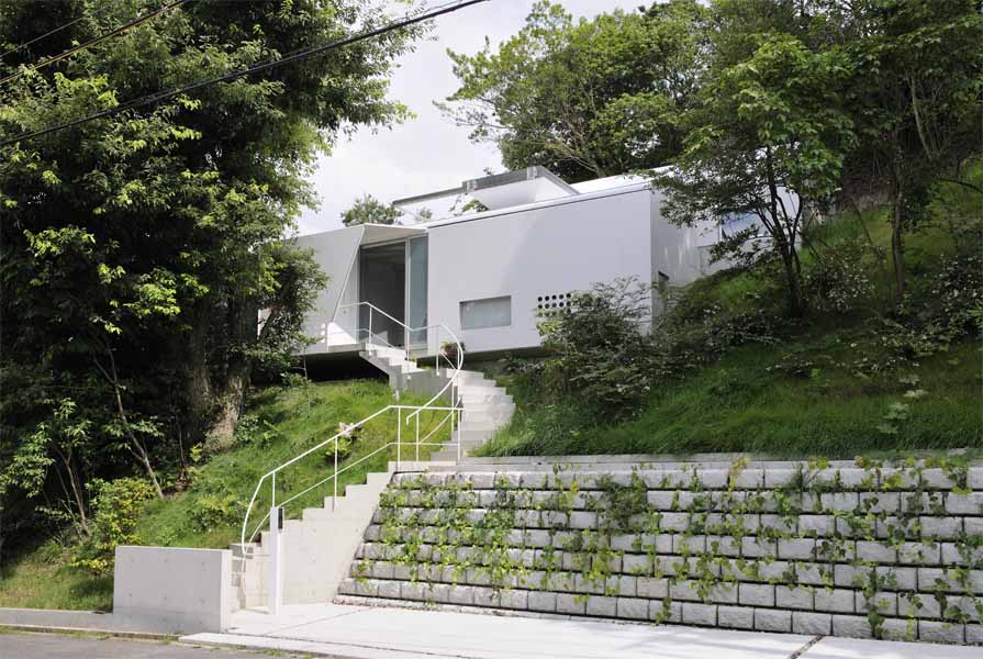 Steel Truss この住宅は、山間の自然木を残した傾斜地に建つ。場所性のもつポテンシャルから、樹木をイメージするオーガニックな意匠性と構造体が連続するような空間を考えた。そして、この大きなスチールトラスの大屋根を、サニタリースペースと茶室に見立てたゲスト室の2つのモノコック構造のスチールボックスが支えている。<br />四畳半のこの鉄の茶室は、厚さ6mmのスチールプレートで一体成型され、運搬、板材の規格寸法、溶接等を複合的に考慮して、ヴォリュームを決定している。ほこらのようなプライベート性の高いこの茶室のトップライトを開放すると、ダイレクトに自然の気配が侵入する中庭空間へと反転し、閉鎖性は一気に開放される。 開口部を構成する要素を視線からなくし、ピクチャーフレームで切り取ったエッジのディテールによって、自然の揺らぎの変化がより敏感に五感に作用し、意識を無限に開放する空間を期待した。<br /><br />設計するにあたり、鋼構造を選択した理由をひとことで言えば、材料の確かさである。高強度や高耐久性はもちろん、鉄の加工技術の発展で変化自在であり、加工精度の正確さ、そして、建築パーツのプロダクト的な工場制作が可能である。またさらに、現場施工の簡略化、素材自身のクオリティやコスト面など総合的に捉えれば、私自身、最も信頼のおける、優れものの建築材料であると考えている。<br />今後、鉄を用いてつくってみたい空間は、従来の柱、梁の規制に捉われない、構造から解き放たれた建築。たとえば、モノッコック的な建築の試みの、船や車、乗り物のような面で包まれた大空間であり、その無限の可能性に魅力を感じている。一方で、無機質なクールな素材であるが、自然や五感に連動した空間を目指したい。