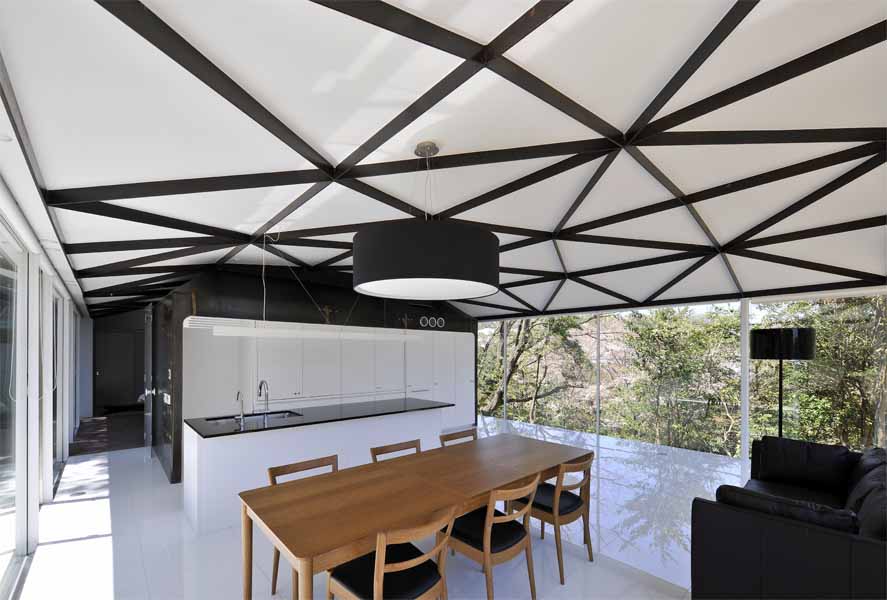 Steel Truss この住宅は、山間の自然木を残した傾斜地に建つ。場所性のもつポテンシャルから、樹木をイメージするオーガニックな意匠性と構造体が連続するような空間を考えた。そして、この大きなスチールトラスの大屋根を、サニタリースペースと茶室に見立てたゲスト室の2つのモノコック構造のスチールボックスが支えている。<br />四畳半のこの鉄の茶室は、厚さ6mmのスチールプレートで一体成型され、運搬、板材の規格寸法、溶接等を複合的に考慮して、ヴォリュームを決定している。ほこらのようなプライベート性の高いこの茶室のトップライトを開放すると、ダイレクトに自然の気配が侵入する中庭空間へと反転し、閉鎖性は一気に開放される。 開口部を構成する要素を視線からなくし、ピクチャーフレームで切り取ったエッジのディテールによって、自然の揺らぎの変化がより敏感に五感に作用し、意識を無限に開放する空間を期待した。<br /><br />設計するにあたり、鋼構造を選択した理由をひとことで言えば、材料の確かさである。高強度や高耐久性はもちろん、鉄の加工技術の発展で変化自在であり、加工精度の正確さ、そして、建築パーツのプロダクト的な工場制作が可能である。またさらに、現場施工の簡略化、素材自身のクオリティやコスト面など総合的に捉えれば、私自身、最も信頼のおける、優れものの建築材料であると考えている。<br />今後、鉄を用いてつくってみたい空間は、従来の柱、梁の規制に捉われない、構造から解き放たれた建築。たとえば、モノッコック的な建築の試みの、船や車、乗り物のような面で包まれた大空間であり、その無限の可能性に魅力を感じている。一方で、無機質なクールな素材であるが、自然や五感に連動した空間を目指したい。