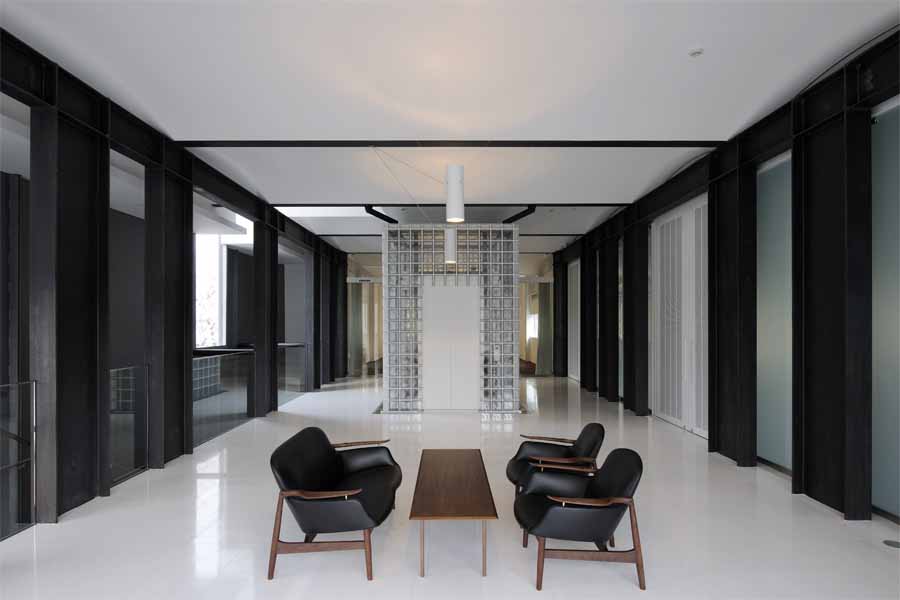 京都工芸繊維大学創立60周年記念館 60周年記念館は、シンボル的存在として大学中央口前に建つ。大学キャンバス計画に基づき、既存校舎の軸線に合わせ、既存樹木帯を残した外部道路との間に位置している。全体は、一階にメモリアルホール、ギャラリーと記念講義室があり、二階に大小のセミナーホールとそのホワイエラウンジがある。そして、一部構内の外構塀を取払い、直接外部道路からの使用可能な学外に開いた施設である。<br />記念館の構想にあたり、時間をテーマに記憶と時を静止させた時代を再確認する静的な建築であると捕らえた。建築は、過去から継承され失われる技術もあり、当然ながら機能では定まらず、感性、記憶、象徴等と多重的要素で成立している。<br />本大学創設当時の本野清吾設計による校舎は、やや重量感のあるRC造の建築であるが、しかし、W. Gropiusのドイツ工作連盟の透明感のあるFagus FactoryやBauhaus Buildingを想起させる新時代の建築であり、一時代の大学のシンボルとしてあり、当時のデザインスクールとして新たな近代デザインへの可能性を具現且つ体感的に示したものであった。<br />現代建築は、存在性が薄れつつある。しかしながら、建設に携わった職人達の無名の熟練した手の痕跡や建築素材により、建築そのものに命を与え、その空間体感が五感を呼び起こし、人に感動と敬意を促す。此れまで出会ったすばらしい建築は、それらが身体にダイレクトに伝わるものであった。そして、その時代の文化の結晶として残るのである。ここでは、そんな建築への思いと取り組み、空間の素材とディテールを熟考し、現代性の表現として鉄を使い、創設期の本野清吾のRC造の校舎と対称させた。<br />また、その表現として、空間の初原的な型としてのボルト架構の、2つの異なる相対によって、エレガント性とダイナミズム、そして、空間の格式と品格、更には、未来への可能性を暗示出来ればと考えた。